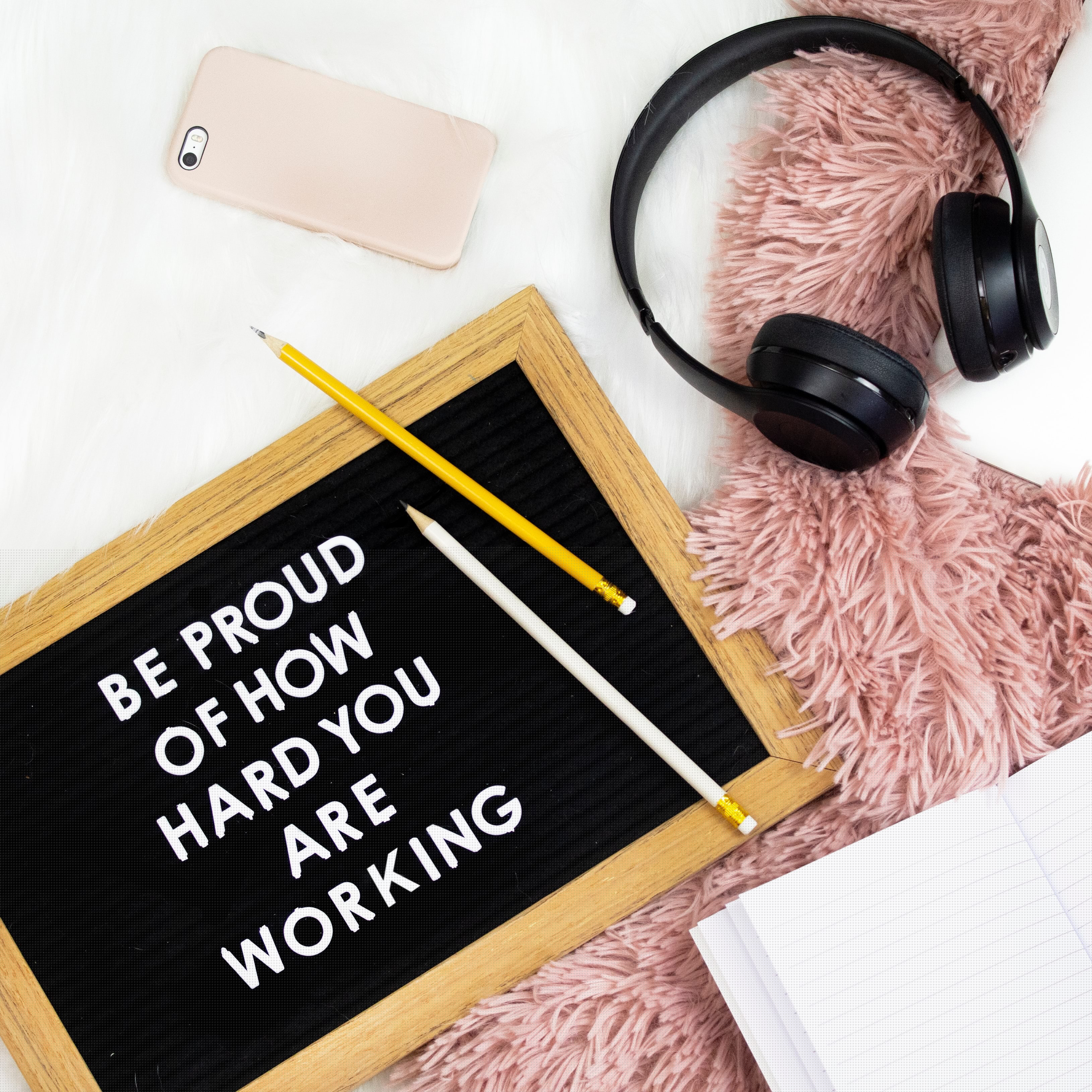 Be proud of how hard you are working sign with headphones and iPhone